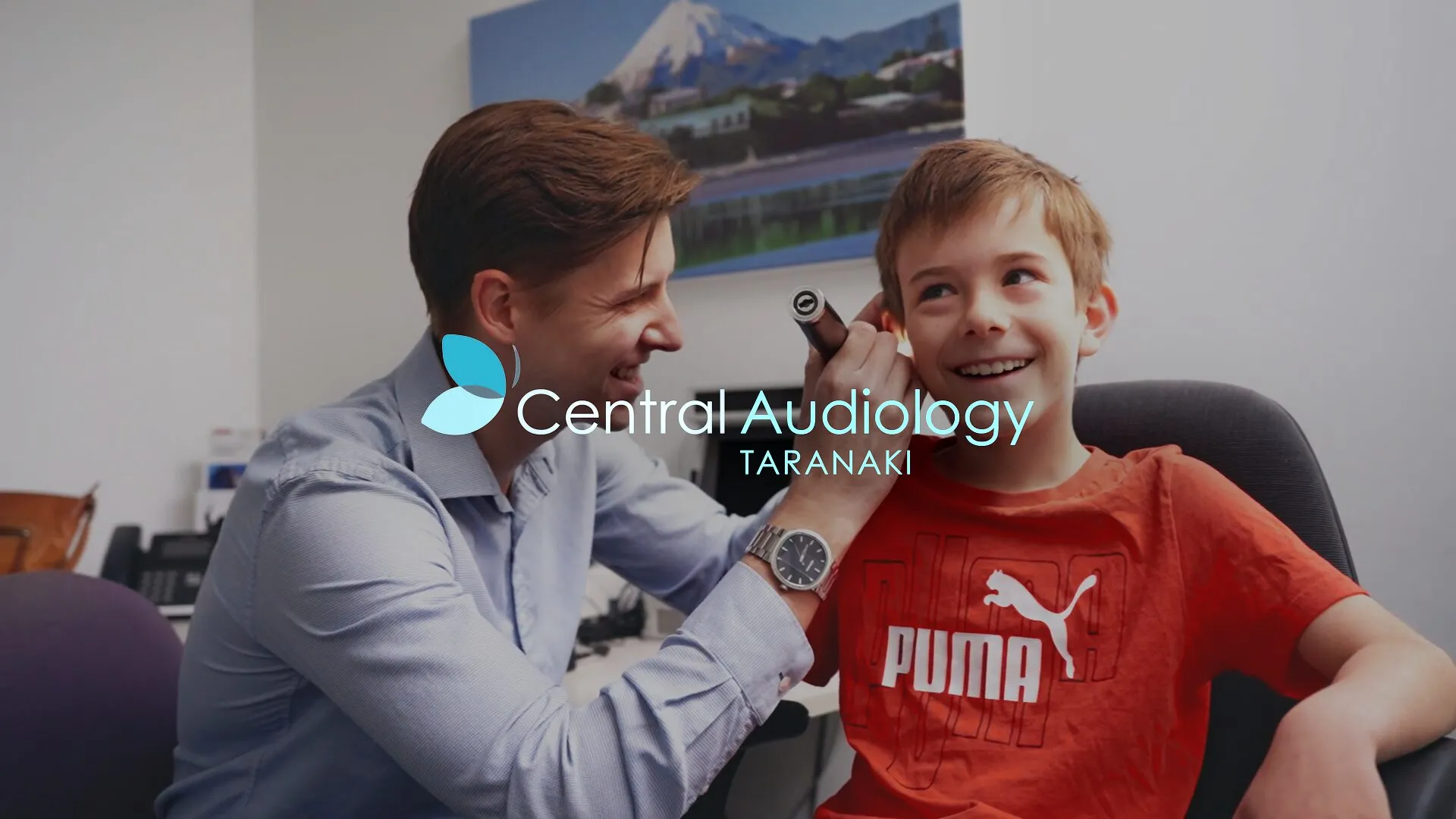 Hilton performing an ear check on a smiling child at Central Audiology in New Plymouth.